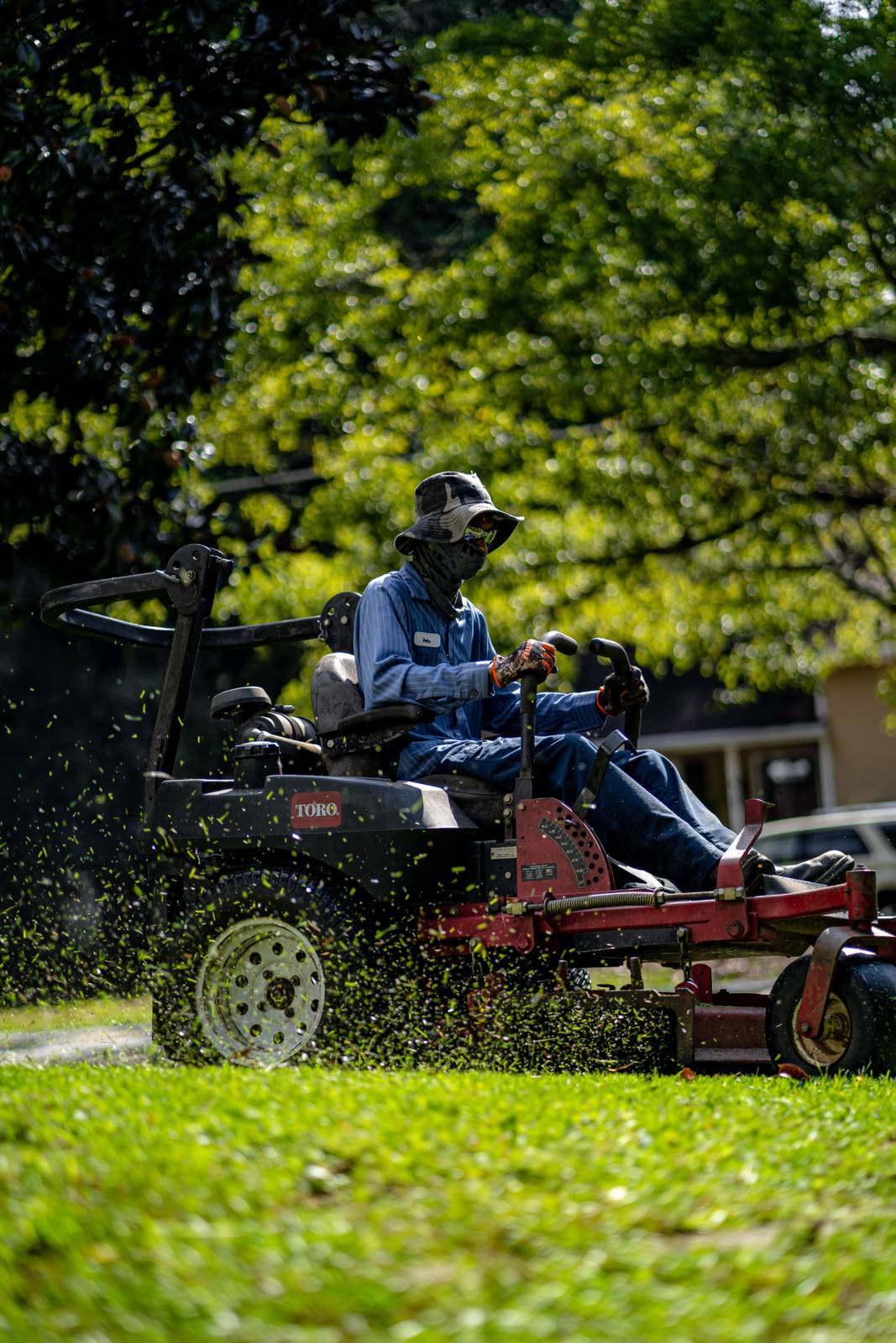 A lawn care operator working a client's property on a ride-on mower